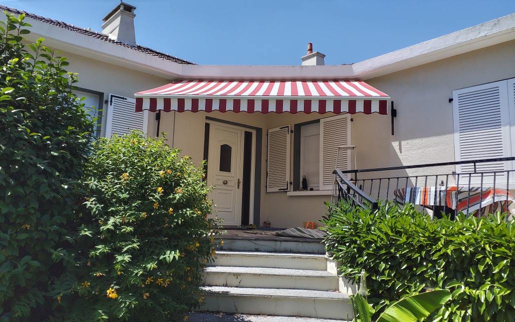 Store banne rayé bordeaux installé sur façade maison — Vendée